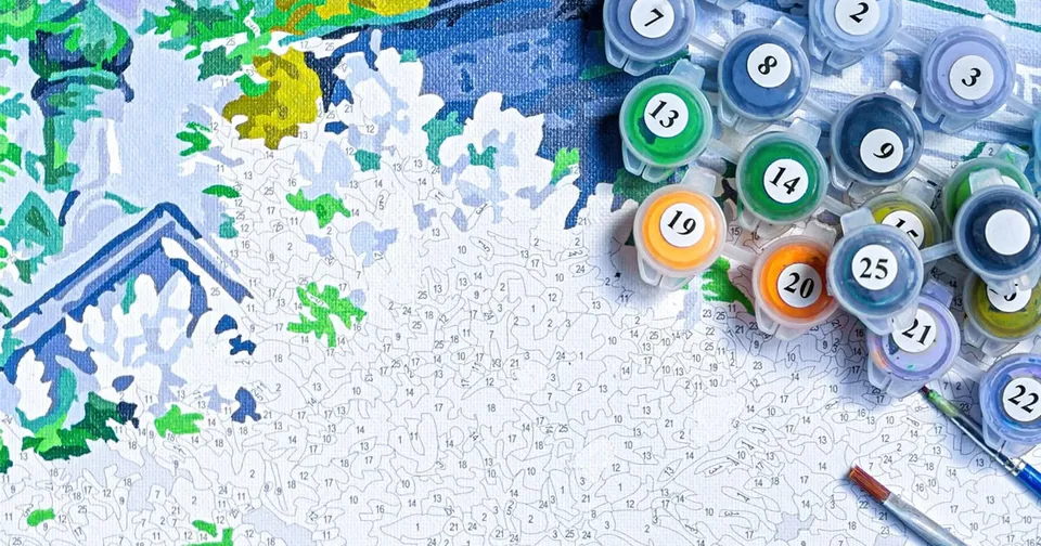 Paint pots and brushes resting on a detailed numbered canvas